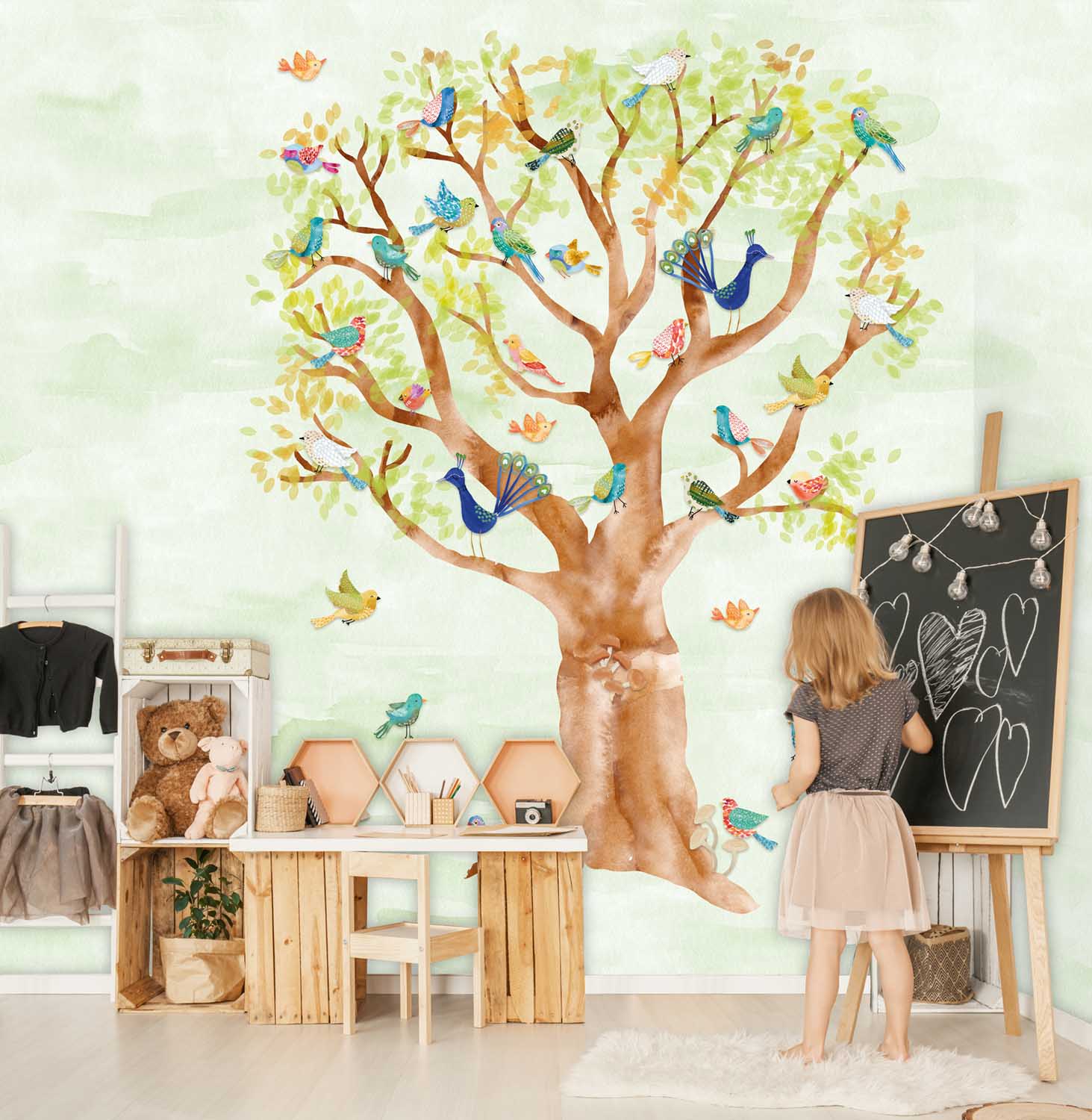 Little girl drawing on a blackboard in her room with wooden boxes, teddy bears and wall stickers